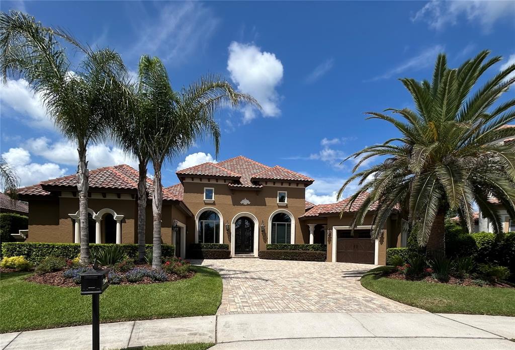 A tan stucco house with a tiled roof, arched windows, and a paved driveway — 25608 GRANDVIEW POINTE, SORRENTO, FL