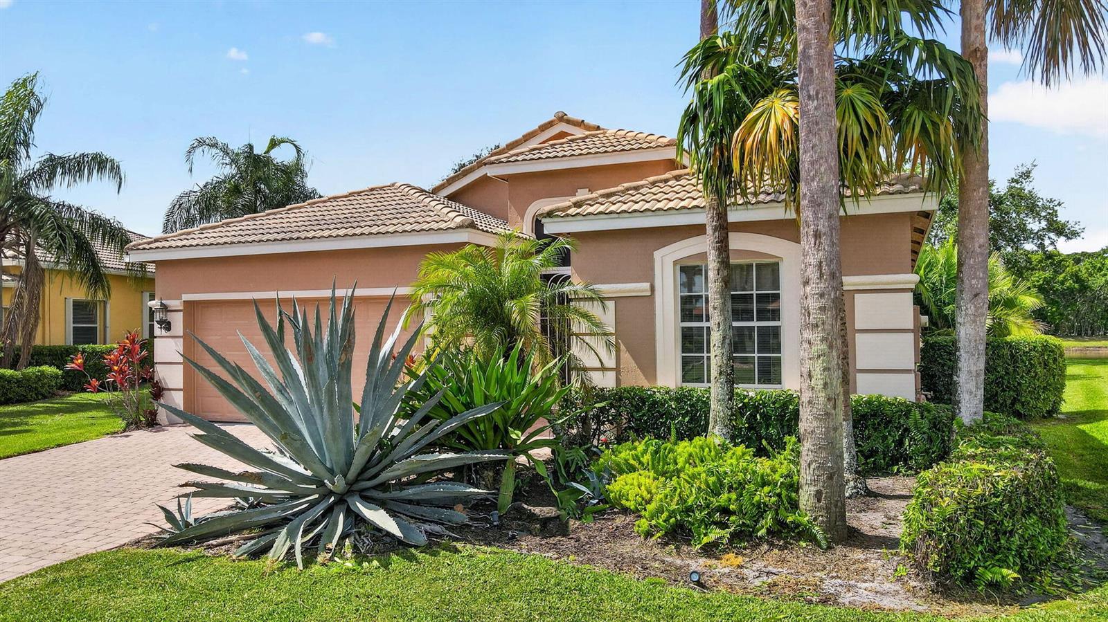 A tan single-story house with a tile roof, a two-car garage, and tropical landscaping — 8216 Parini Way, Lake Worth FL 33467, LAKE WORTH, FL