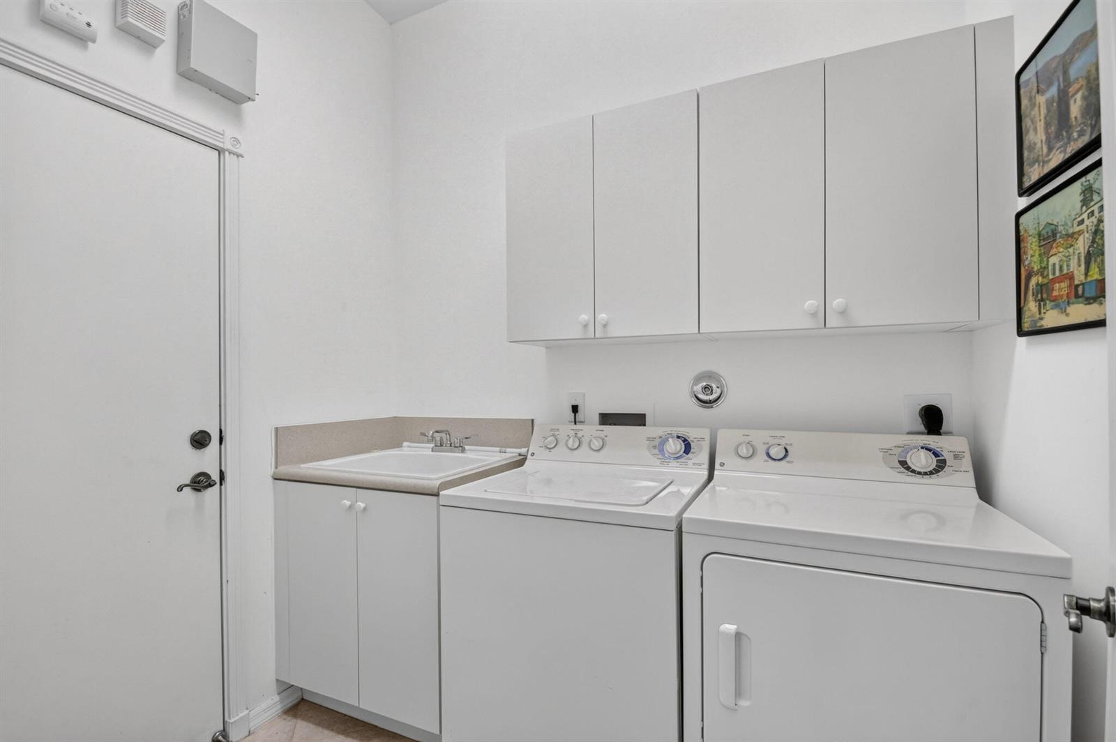 A laundry room features white cabinets, a utility sink, and a washer and dryer set — 8216 Parini Way, Lake Worth FL 33467, LAKE WORTH, FL