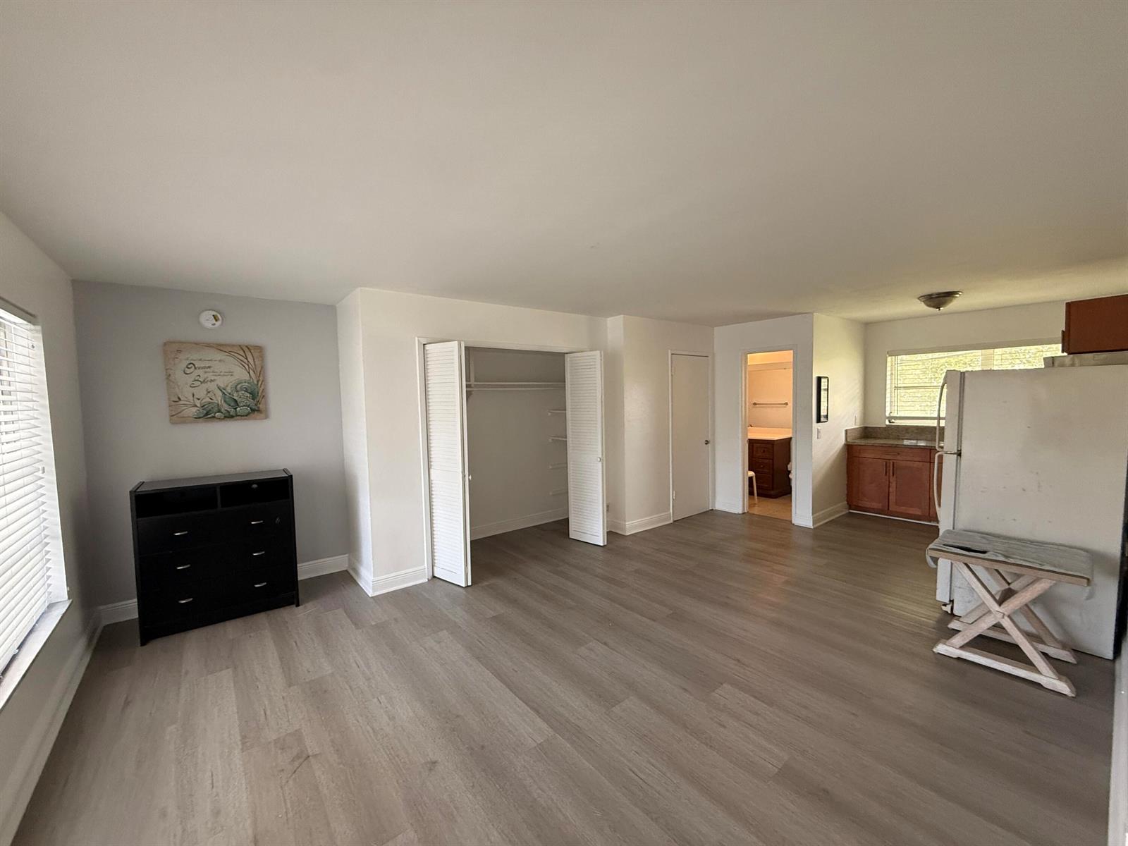 An open-concept studio apartment features light wood-look flooring, a closet, and a small kitchen — 3226 NE 12th Street # 10, Pompano Beach FL 33062, POMPANO BEACH, FL