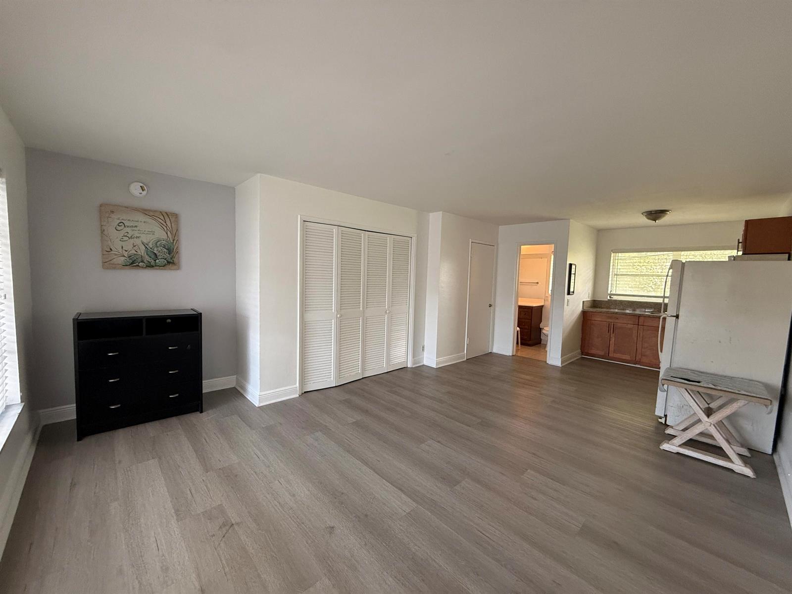 An open-concept living area features light wood-look flooring, white walls, and an adjacent kitchen — 3226 NE 12th Street # 10, Pompano Beach FL 33062, POMPANO BEACH, FL