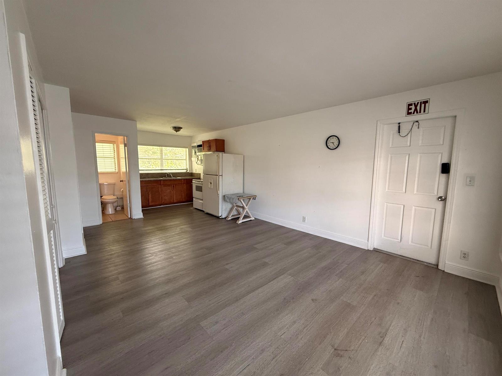 An open-concept studio apartment features wood-look flooring, a small kitchen, and an attached bathroom — 3226 NE 12th Street # 10, Pompano Beach FL 33062, POMPANO BEACH, FL