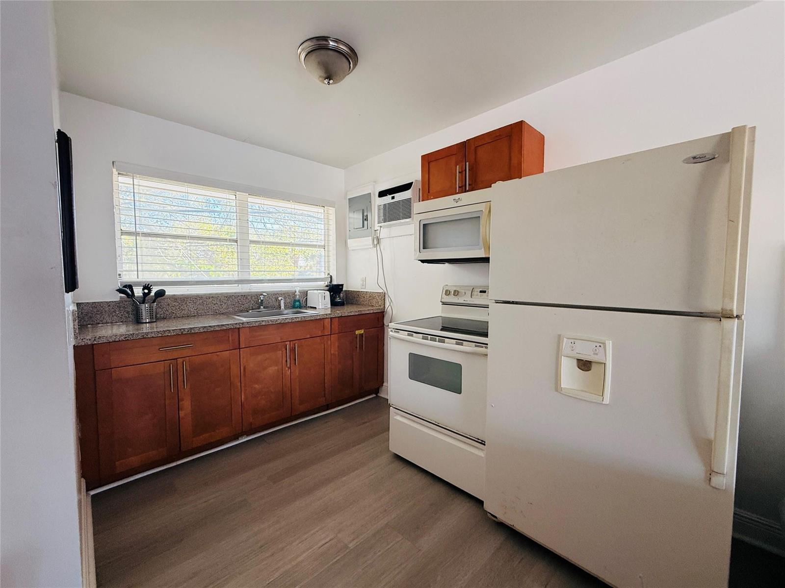 A kitchen features wood cabinets, granite countertops, white appliances, and a window above the sink — 3226 NE 12th Street # 10, Pompano Beach FL 33062, POMPANO BEACH, FL