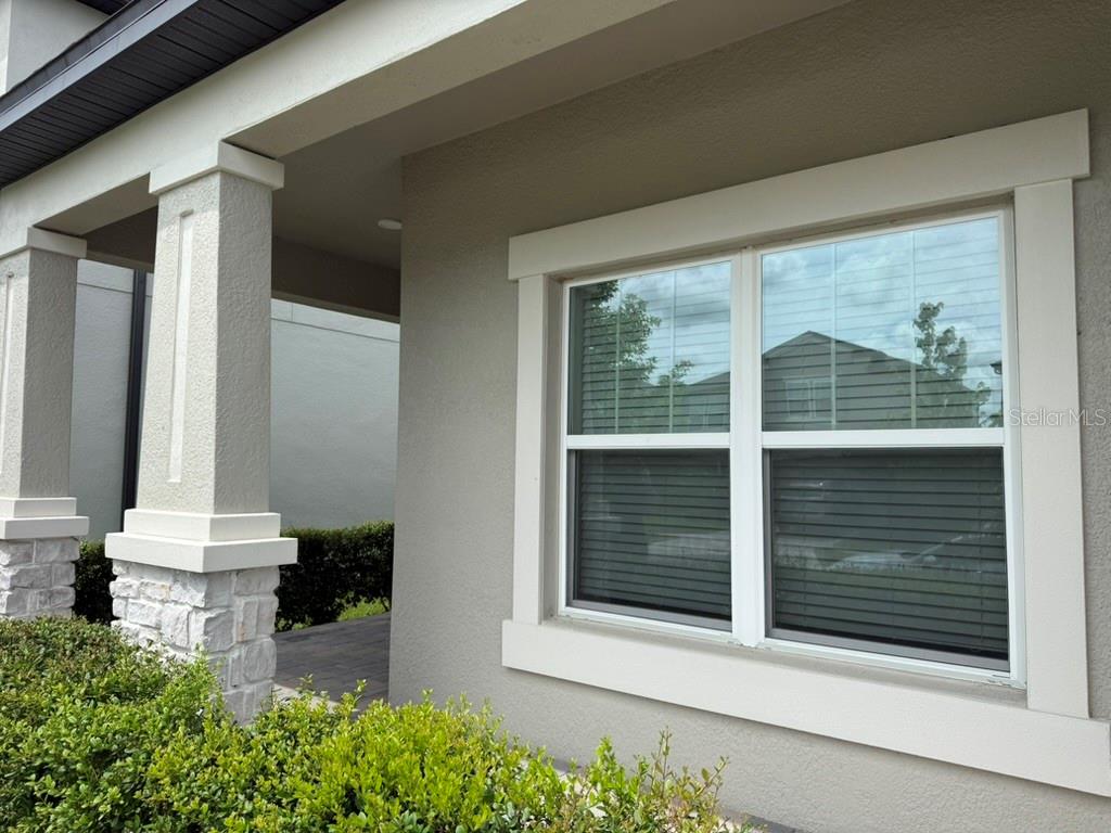 A view of a house exterior featuring a stone-based column and a double-hung window — 7749 BRONZE OAK DRIVE, WESLEY CHAPEL, FL