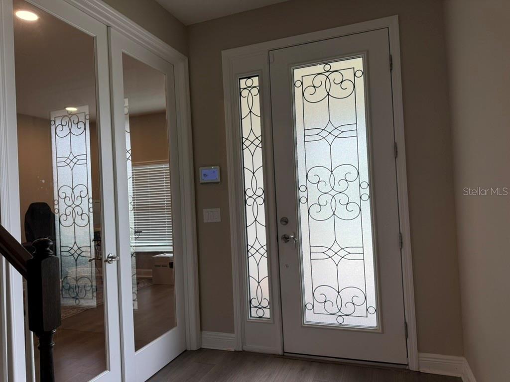 An entryway features a white front door with decorative glass panels and matching sidelights — 7749 BRONZE OAK DRIVE, WESLEY CHAPEL, FL