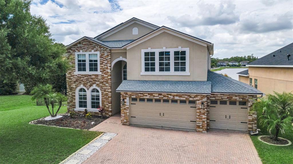 A two-story house with a stone facade, a three-car garage, and a brick paver driveway — 1345 HALAPA WAY, TRINITY, FL