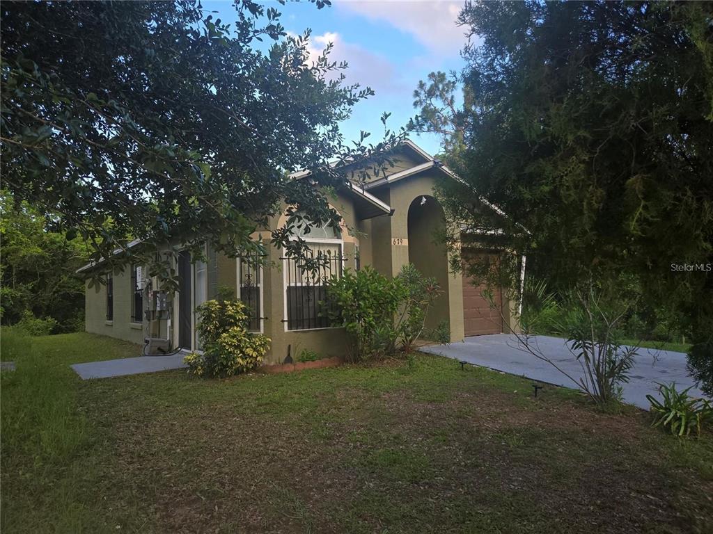 A single-story house with a green exterior, a garage, and security bars on the windows — 679 MIDORI STREET, ORLANDO, FL