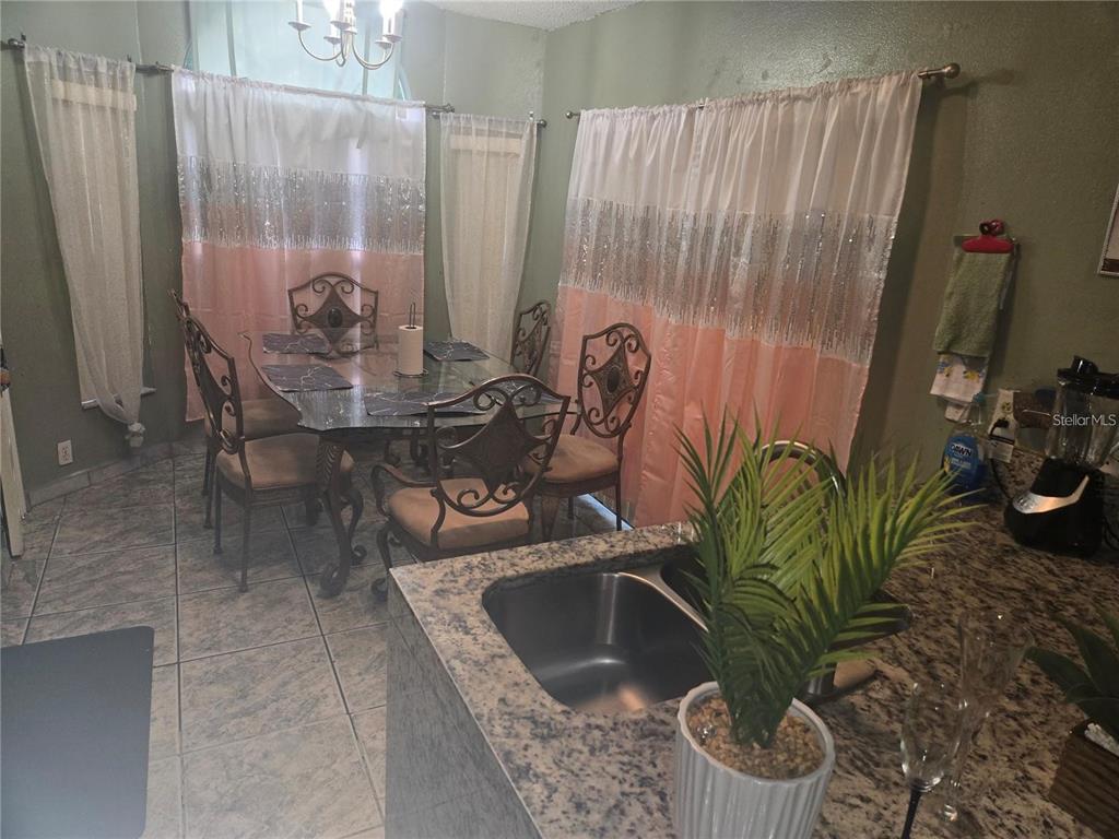 A dining area with a glass table and metal chairs sits beside a kitchen counter — 679 MIDORI STREET, ORLANDO, FL