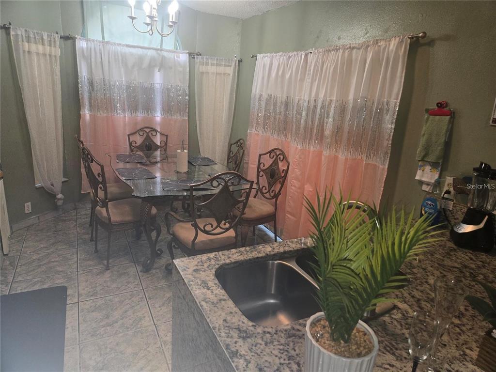 A dining area features a glass-top table, metal chairs, and curtains with sequin accents — 679 MIDORI STREET, ORLANDO, FL
