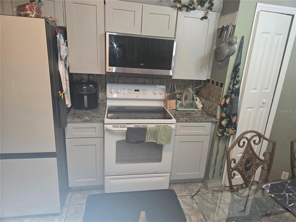 A kitchen features light gray cabinets, a white electric range, and a stainless steel microwave — 679 MIDORI STREET, ORLANDO, FL