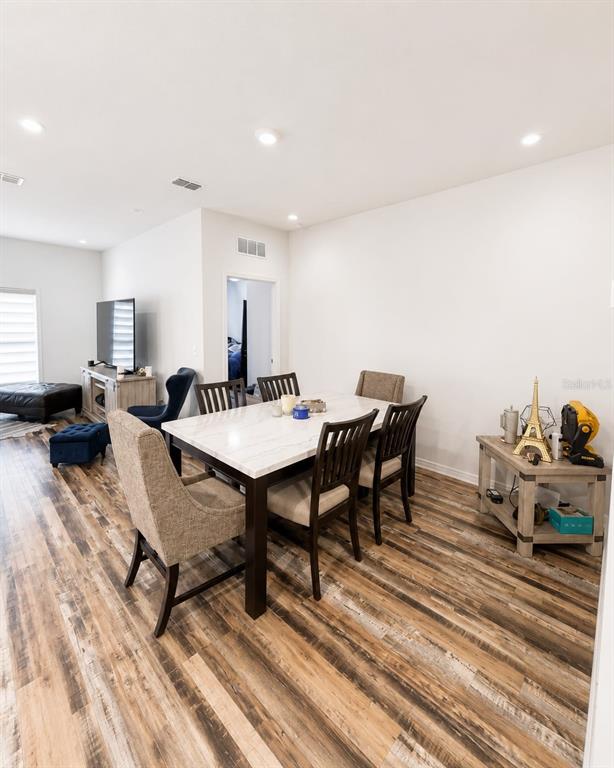 A dining area features a marble-topped table, upholstered chairs, and wood-look flooring — 5882 HERDER ROAD, ST CLOUD, FL
