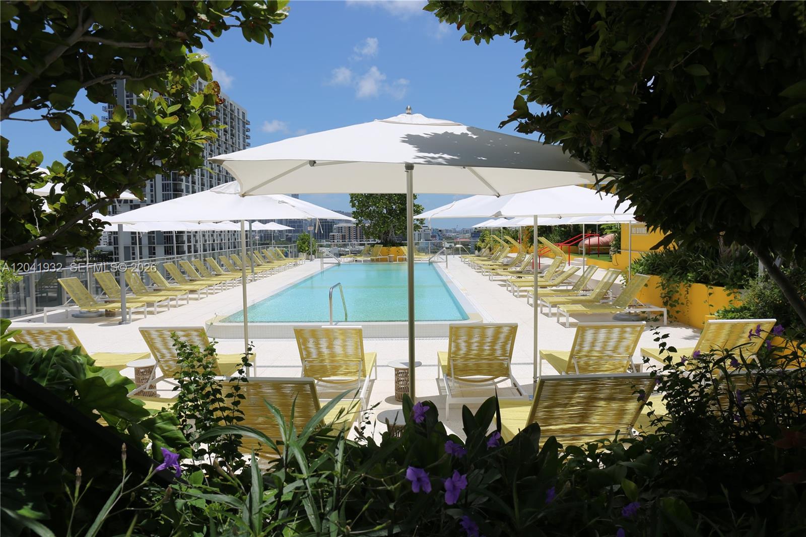 A rooftop swimming pool surrounded by lounge chairs and white umbrellas under a blue sky — 90 NE 32nd St # 802, Miami FL 33137, MIAMI, FL