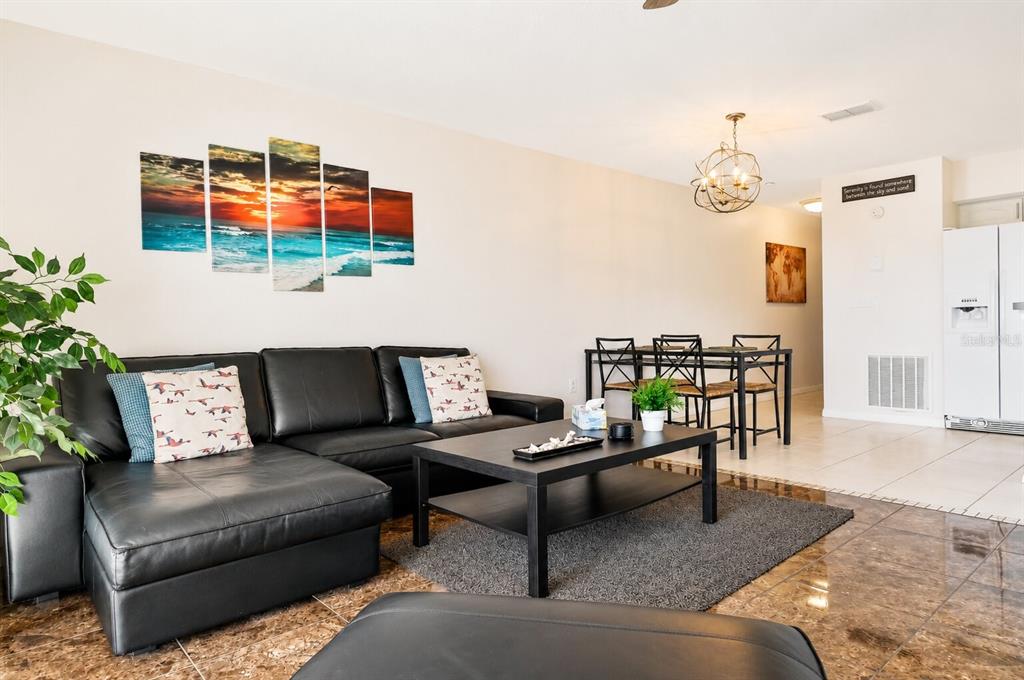 A living room features a black sectional sofa, a coffee table, and a dining area — 19811 GULF BOULEVARD UNIT 102, INDIAN SHORES, FL
