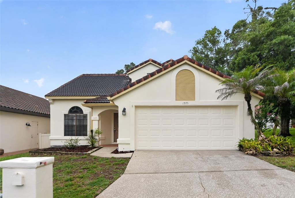 A single-story house with a white stucco exterior, a tile roof, and a two-car garage — 1375 AUGUSTA NATIONAL BOULEVARD, WINTER SPRINGS, FL