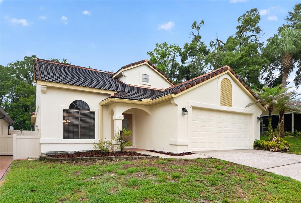 A single-story stucco house with a tiled roof, arched entryway, and attached two-car garage — 1375 AUGUSTA NATIONAL BOULEVARD, WINTER SPRINGS, FL