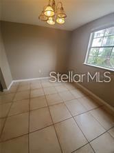An empty dining room features beige tile flooring, light-colored walls, and a multi-light chandelier — 3984 VERSAILLES DRIVE UNIT 3984C, ORLANDO, FL