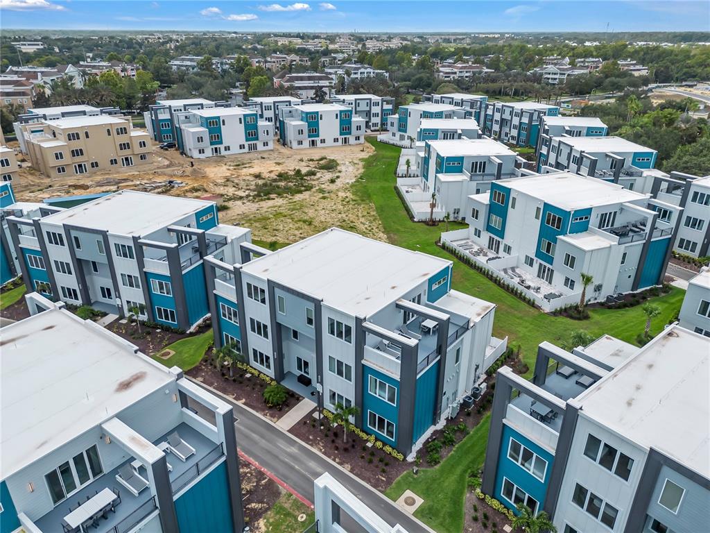 An aerial view shows multiple modern, multi-story apartment buildings with blue and white exteriors — 7740 SANDY RIDGE DRIVE UNIT 228, KISSIMMEE, FL