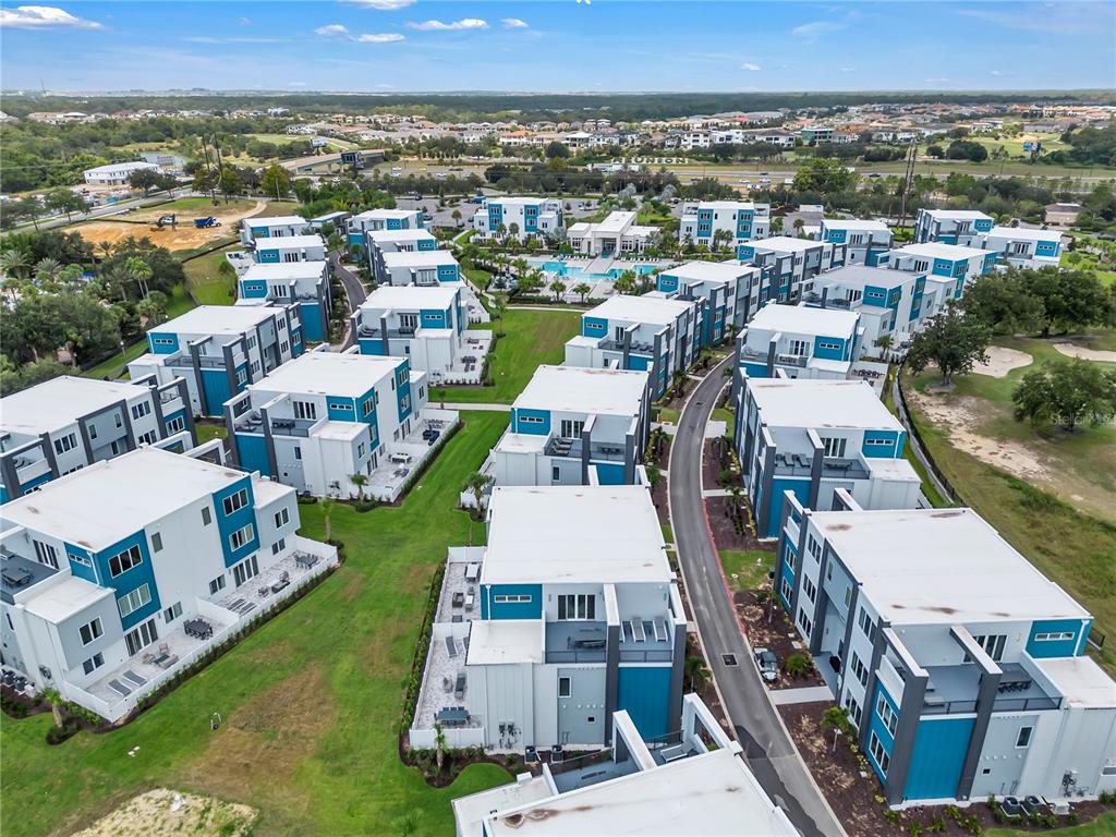 An aerial view shows a modern residential complex with white and blue multi-story buildings — 7740 SANDY RIDGE DRIVE UNIT 228, KISSIMMEE, FL