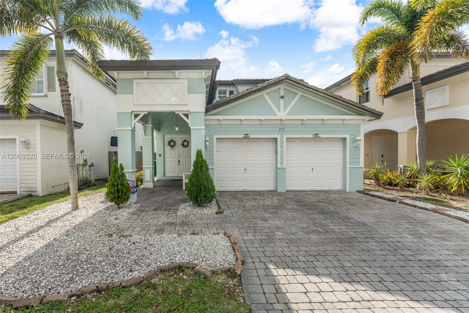 A light blue two-story house features a two-car garage and a paved driveway — 216 NE 36th Ter, Homestead FL 33033, HOMESTEAD, FL
