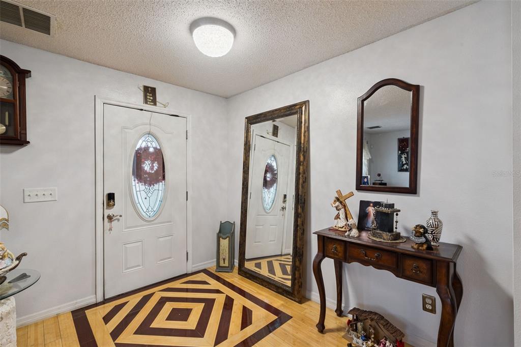 An entryway features a white front door, a large floor mirror, and a wooden console table — 7506 FORDHAM CREEK LANE, ORLANDO, FL