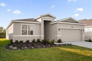A single-story house with a light gray exterior, a two-car garage, and a front lawn — 4385 PEBBLES THROW DRIVE UNIT B, KISSIMMEE, FL