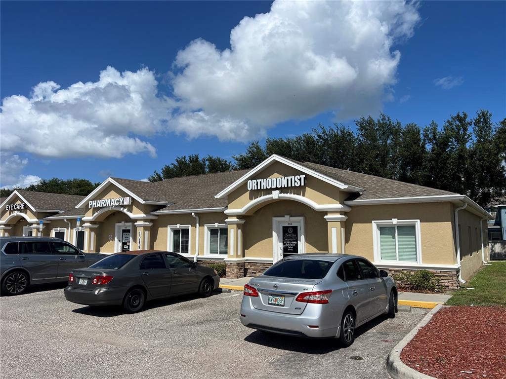 A single-story commercial building with a stone-veneer base, white walls, and a covered entrance — 13135 KINGS LAKE DRIVE UNIT 103, GIBSONTON, FL