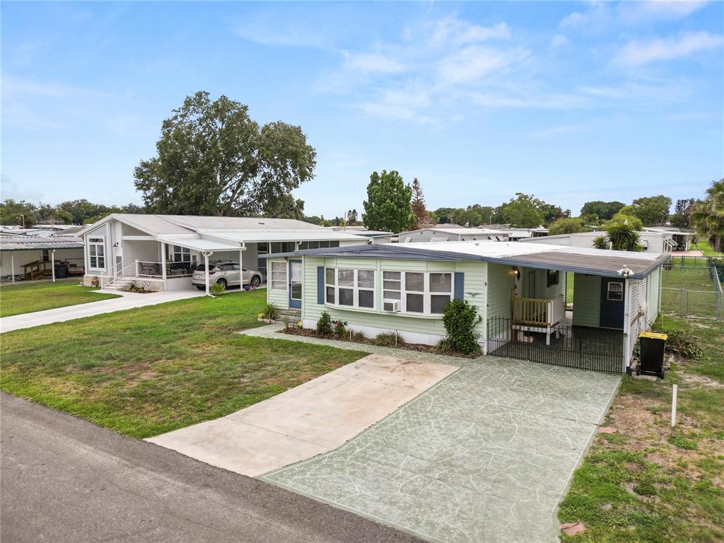 A light green mobile home with a carport and concrete driveway sits on a grassy lot — 1610 REYNOLDS ROAD UNIT 330, LAKELAND, FL