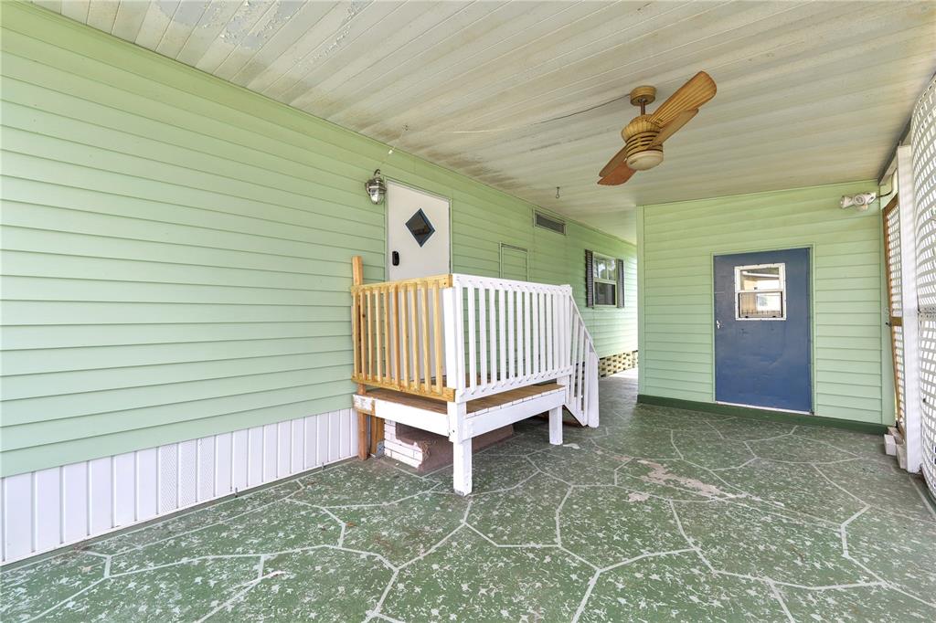 A covered patio with green siding, a small white wooden deck, and a blue door — 1610 REYNOLDS ROAD UNIT 330, LAKELAND, FL