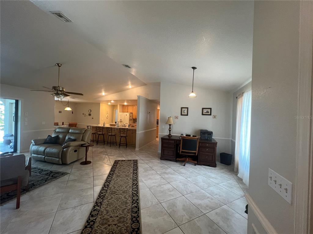 An open-concept living area features tile flooring, a kitchen with bar seating, and a desk — 3177 CLIFFORD STREET, PUNTA GORDA, FL