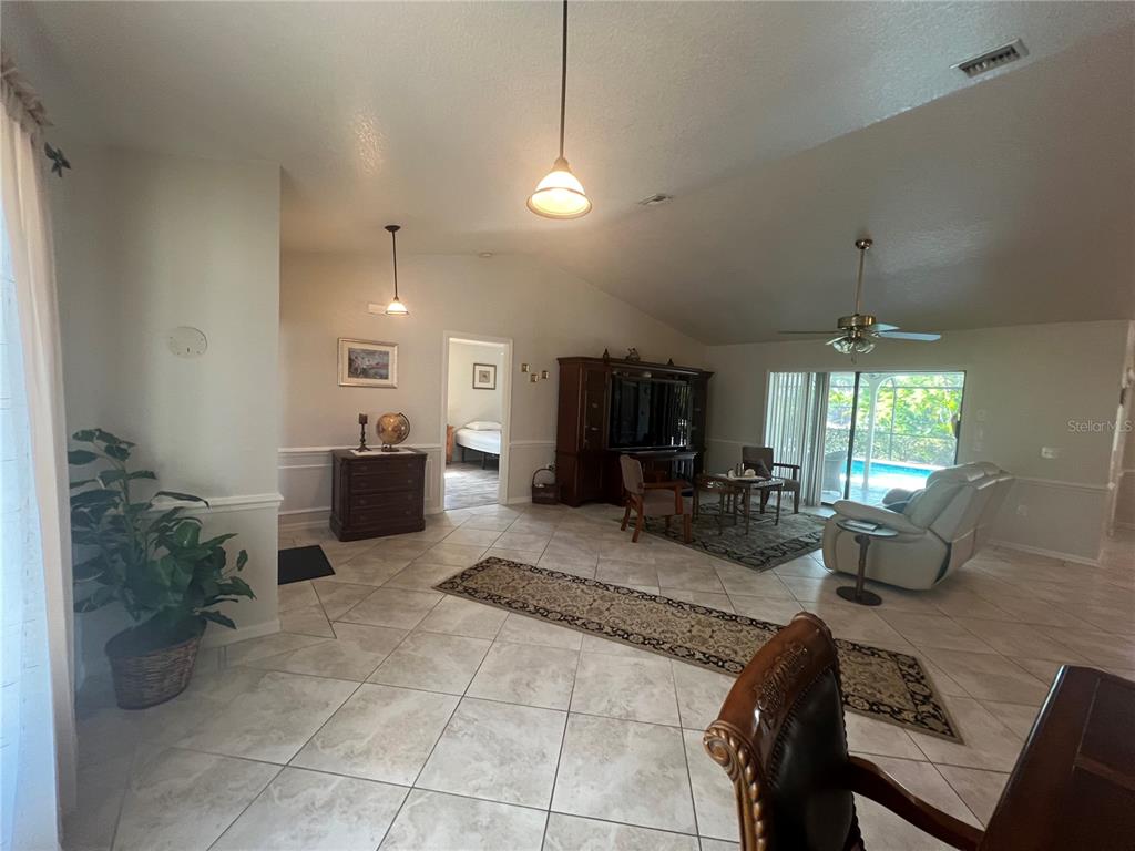 A spacious living room features tile flooring, a vaulted ceiling, and a sliding glass door — 3177 CLIFFORD STREET, PUNTA GORDA, FL