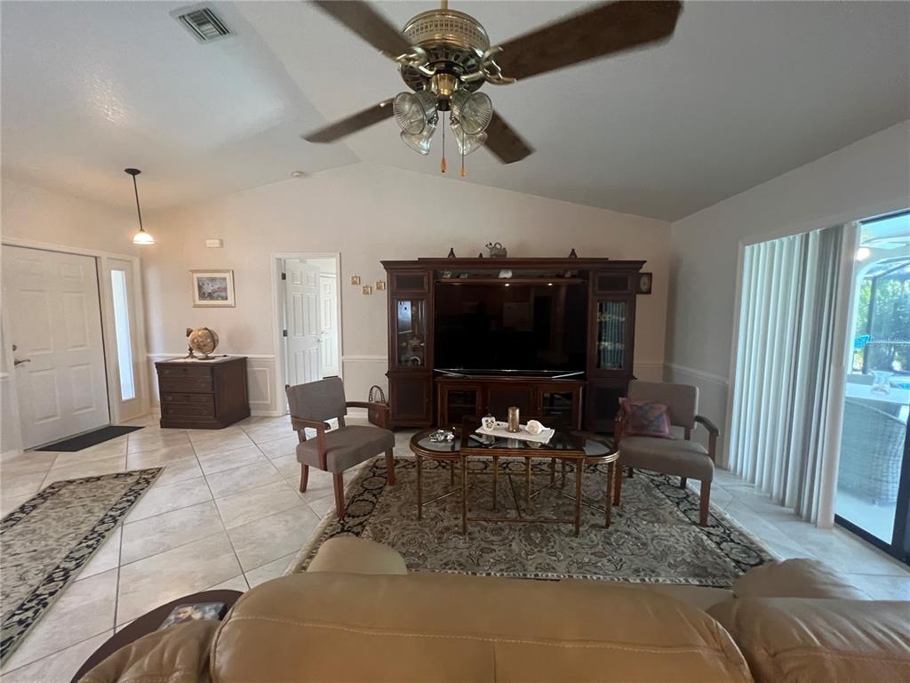 A living room features tile floors, a ceiling fan, a large entertainment center, and chairs — 3177 CLIFFORD STREET, PUNTA GORDA, FL