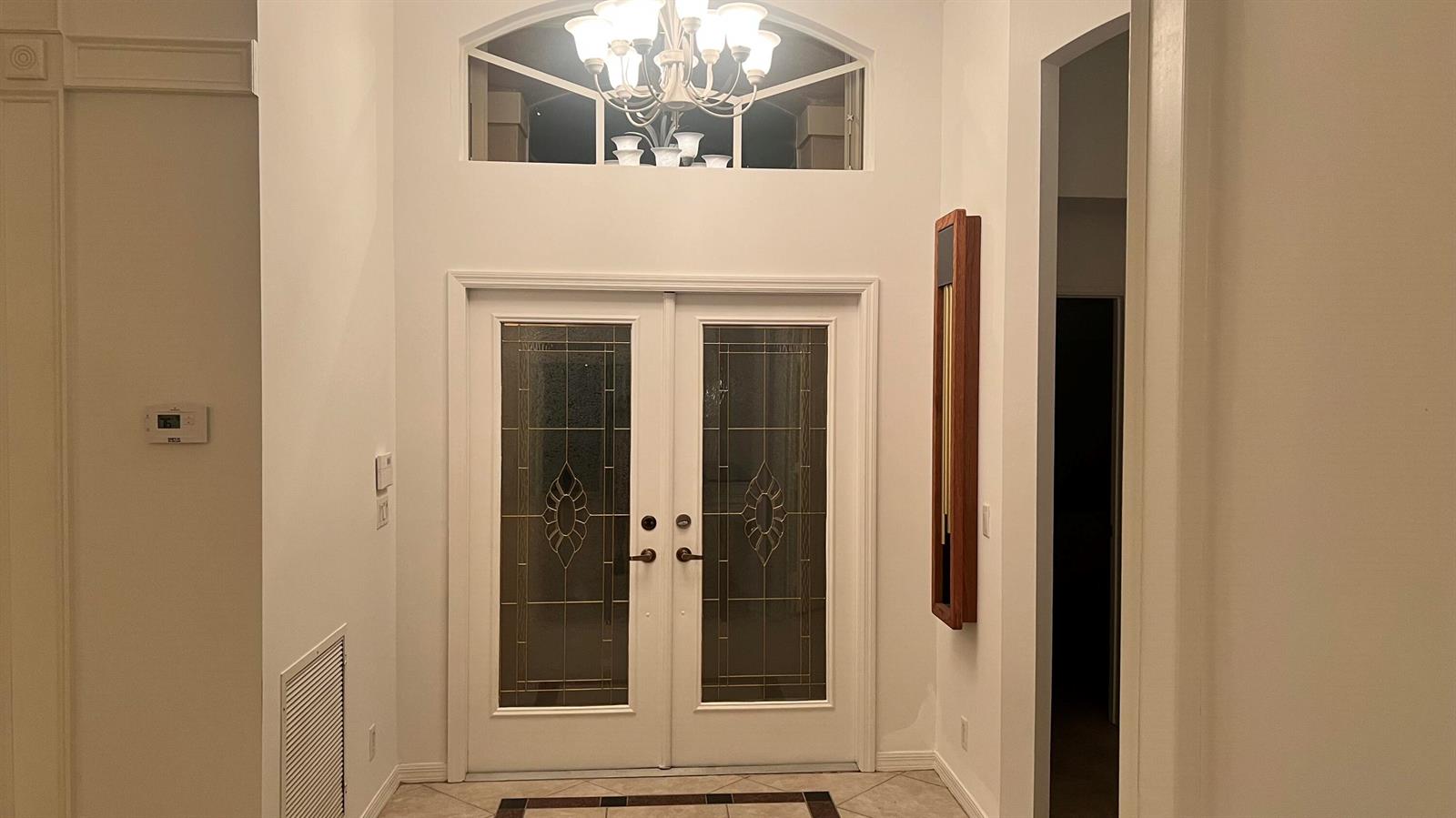 A foyer features double glass-paneled doors, a chandelier, and a transom window above — 6523 Via Trento, Delray Beach FL 33446, DELRAY BEACH, FL