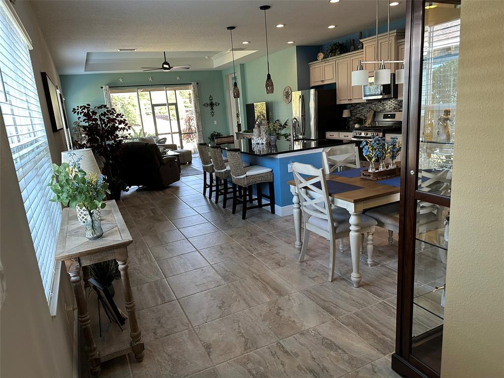 An open-concept kitchen and dining area features tile flooring, blue walls, and a breakfast bar — 13544 OLD CREEK COURT, PARRISH, FL