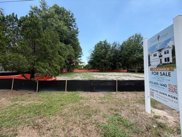 A vacant residential lot is enclosed by a black silt fence with a real estate sign — 1006 W ADALEE STREET, TAMPA, FL