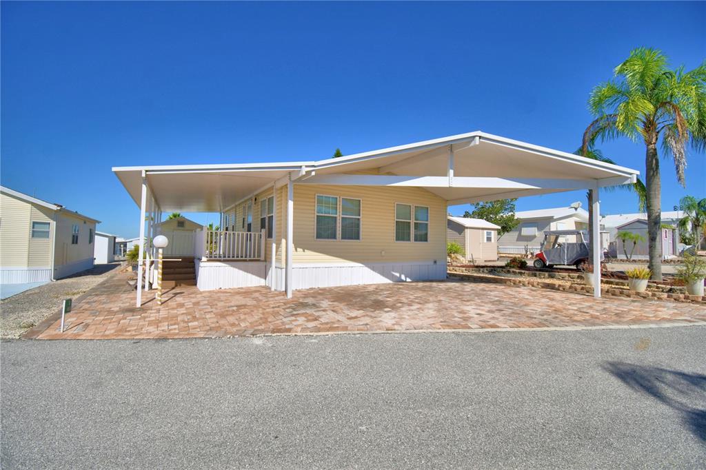 A yellow mobile home with a large covered carport and a brick-paved driveway — 251 PATTERSON ROAD UNIT i46, HAINES CITY, FL
