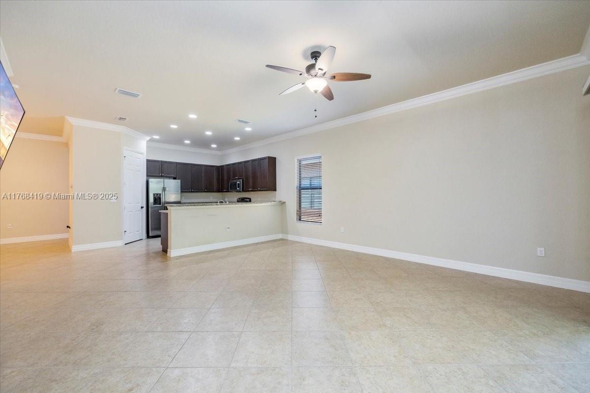 An open-concept living area features tile flooring, a ceiling fan, and a kitchen with cabinets — 13458 Sumter Lane, Naples FL 34109, NAPLES, FL
