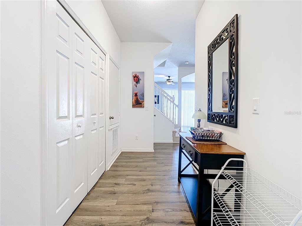 A hallway features wood-look flooring, white paneled doors, a console table, and a wall mirror — 1201 S BEACH CIR, KISSIMMEE, FL
