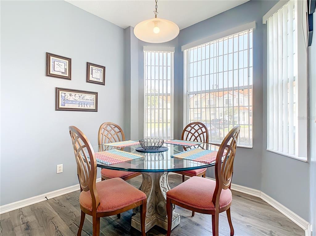 A dining area features a glass-topped table, four wooden chairs, and large windows with blinds — 1201 S BEACH CIR, KISSIMMEE, FL