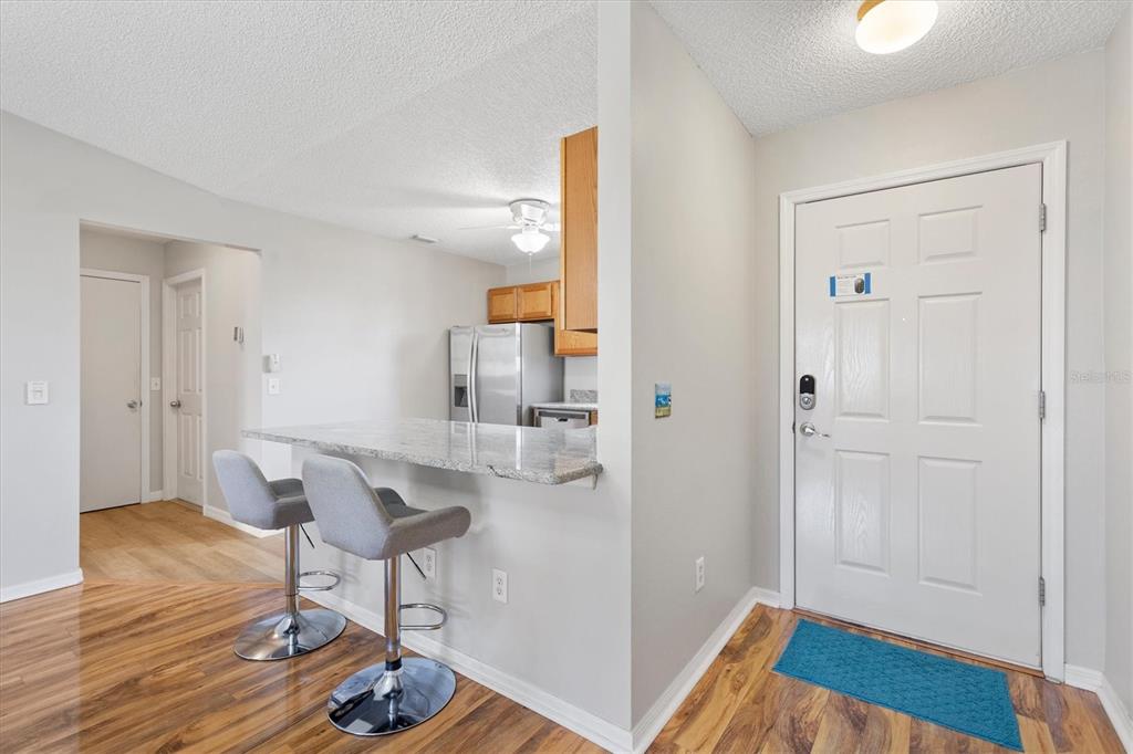 A kitchen with a granite breakfast bar and two stools sits beside an entryway door — 3443 SIPSEY STREET, THE VILLAGES, FL