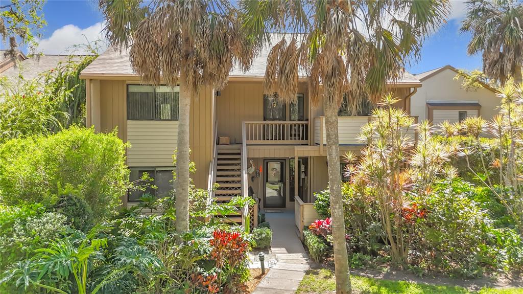 A two-story tan building features an exterior staircase leading to an upper-level balcony and entrance — 1617 BROOKHOUSE DRIVE UNIT BR260, SARASOTA, FL