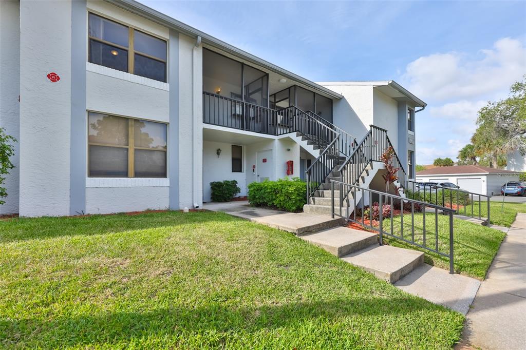 An exterior view of a two-story apartment building with a staircase leading to a balcony — 1934 OYSTER CATCHER STREET UNIT 923, CLEARWATER, FL