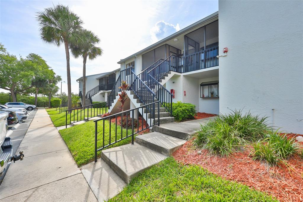 An exterior view of a two-story apartment building with concrete stairs and metal railings — 1934 OYSTER CATCHER STREET UNIT 923, CLEARWATER, FL