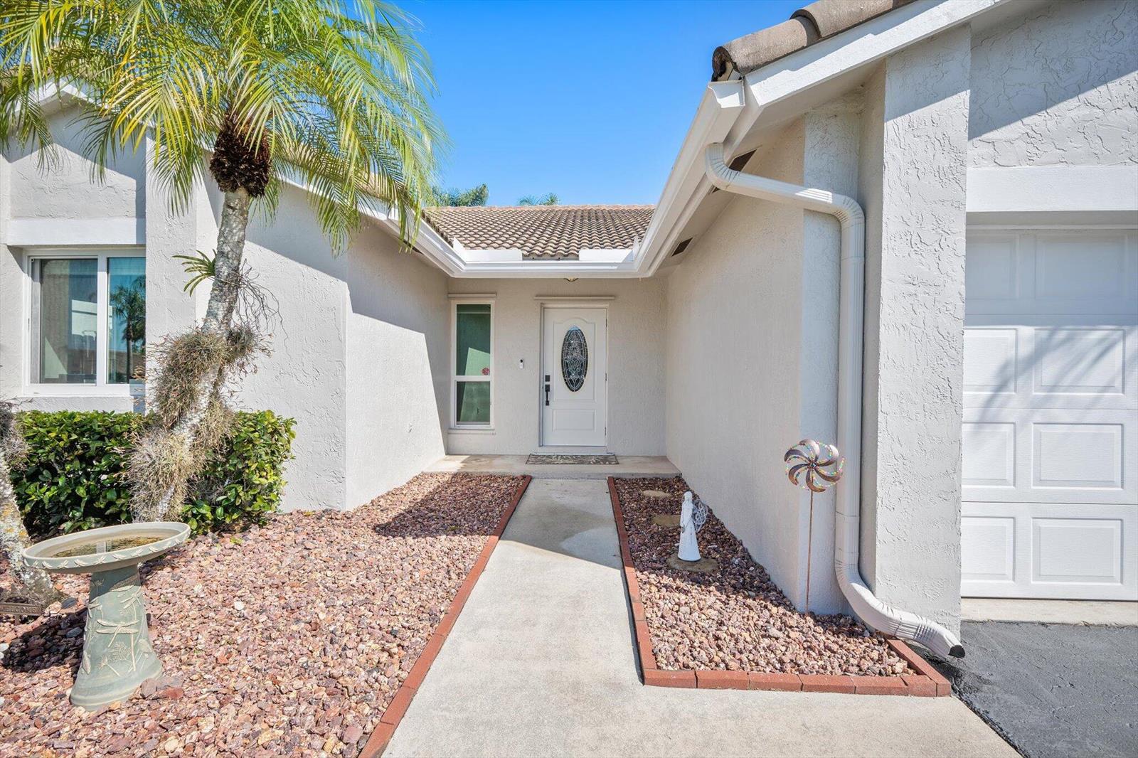 The exterior of a house features a white front door, a walkway, and landscaping — 15541 Dover Court, Davie FL 33331, DAVIE, FL