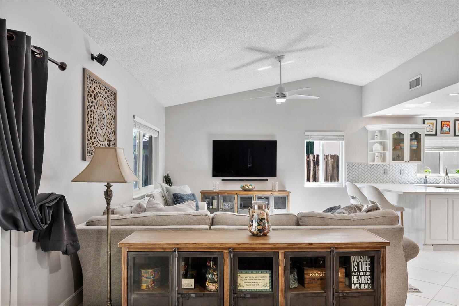 A living room features a vaulted ceiling, a sectional sofa, and a wooden media console — 15541 Dover Court, Davie FL 33331, DAVIE, FL
