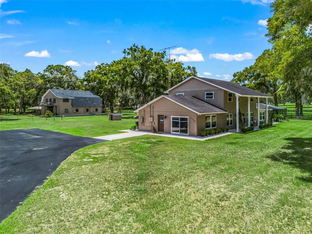 A two-story house and a detached barn sit on a large, grassy, fenced-in property — 12941 SW 8TH AVENUE, OCALA, FL