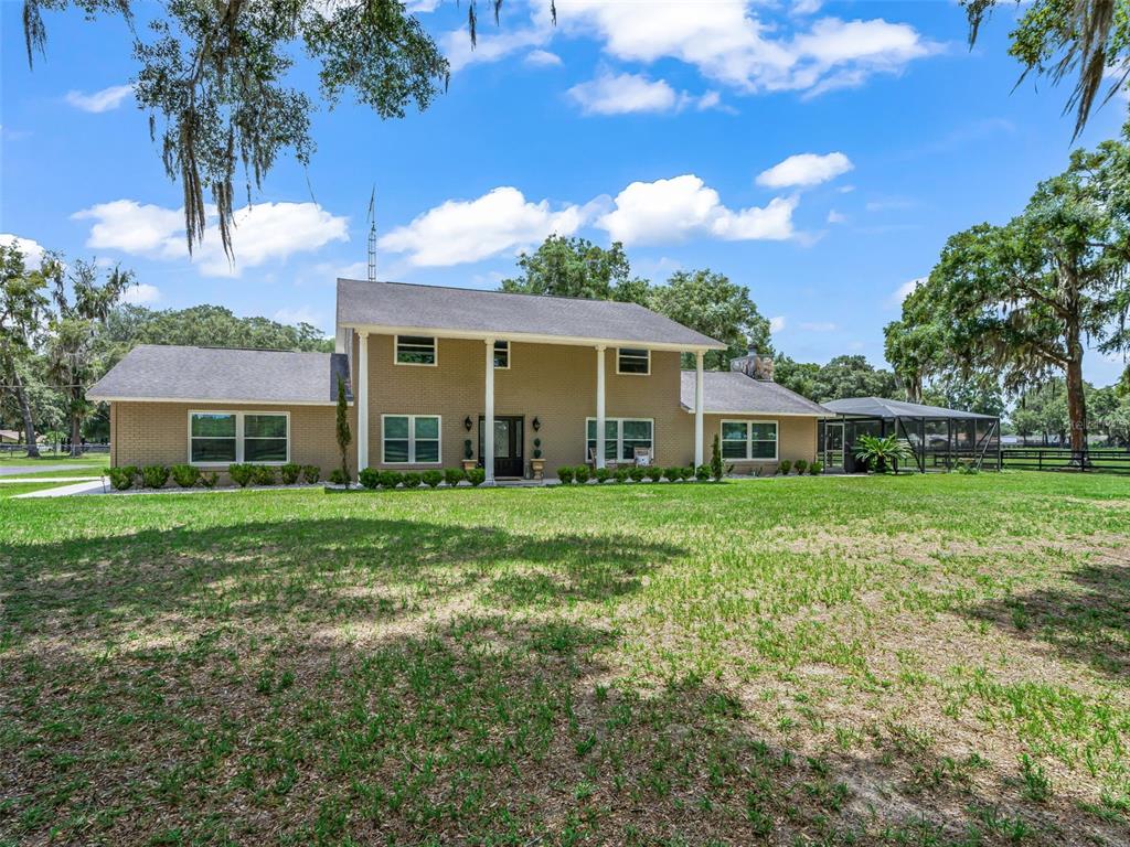 A two-story brick house with a large front lawn and a screened-in patio area — 12941 SW 8TH AVENUE, OCALA, FL