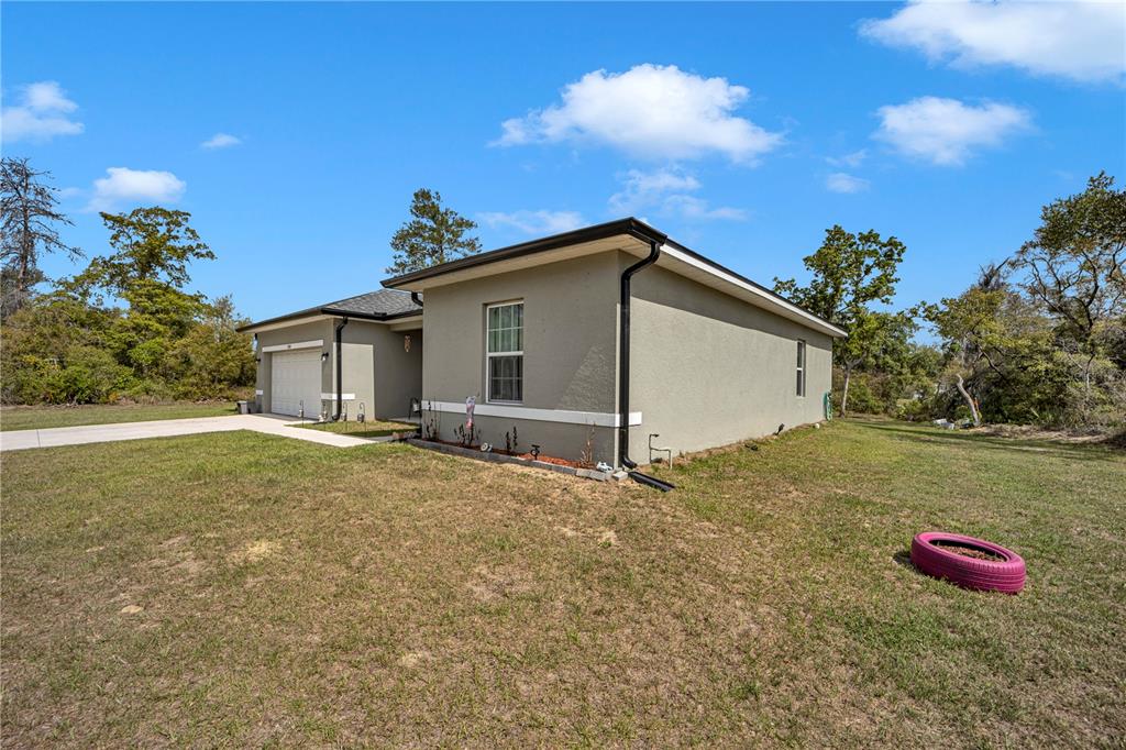 A single-story house with a beige stucco exterior and a garage sits on a lawn — 15841 SW 19TH TERRACE, OCALA, FL
