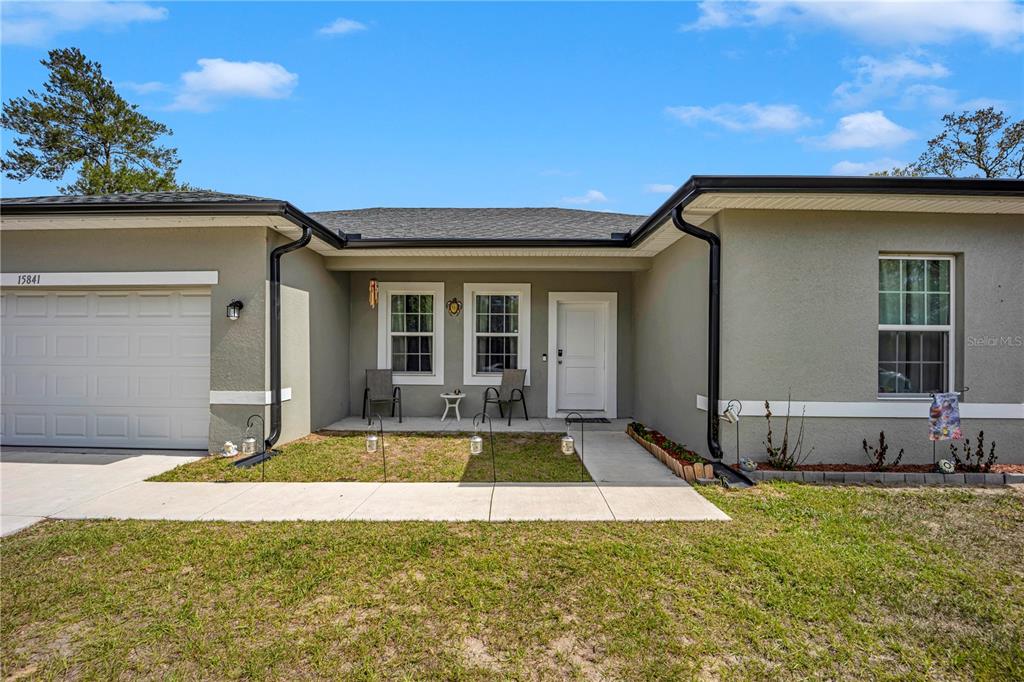 The exterior of a single-story house features a garage, a front porch, and gray siding — 15841 SW 19TH TERRACE, OCALA, FL
