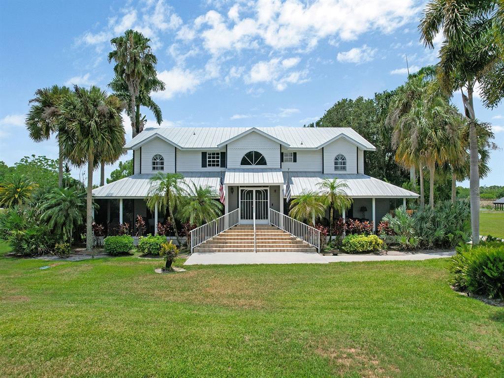 A two-story white house with a metal roof and a large front staircase — 16270 FOREST MIST COURT, ALVA, FL