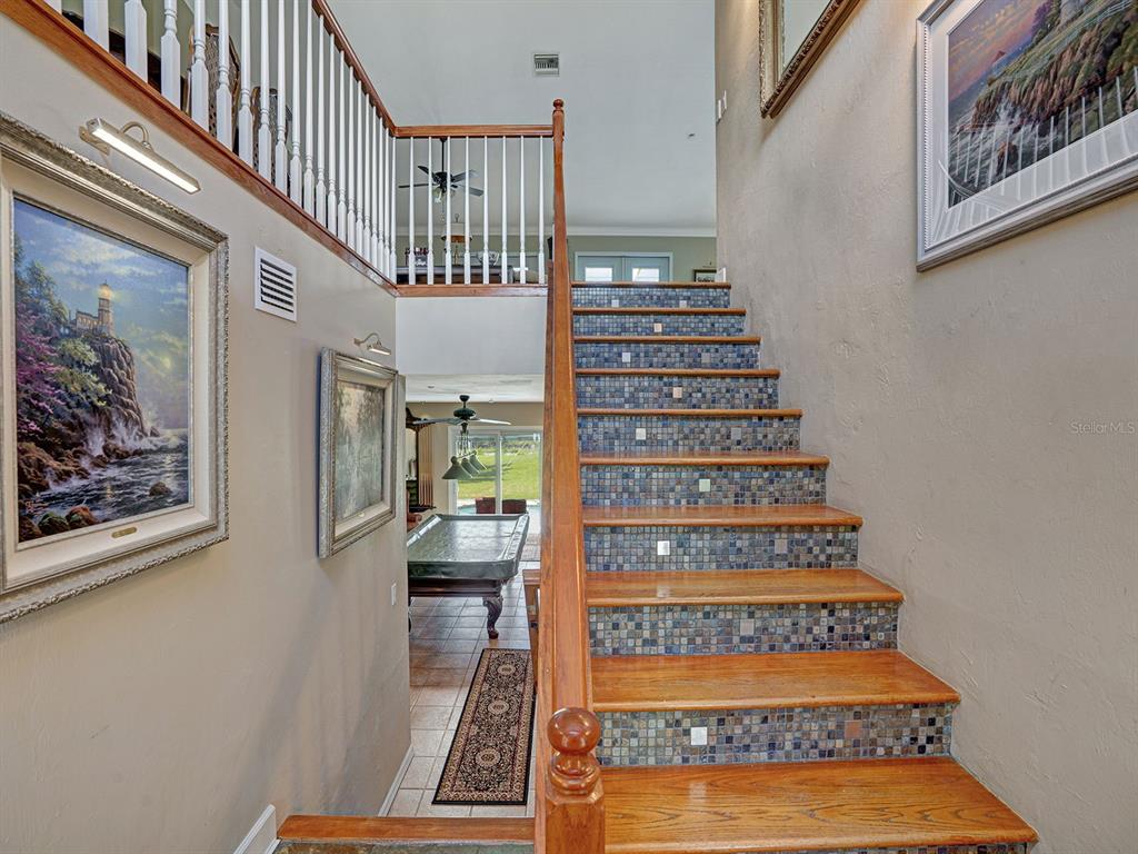 A staircase with wooden treads and mosaic tile risers leads to an upper landing — 16270 FOREST MIST COURT, ALVA, FL